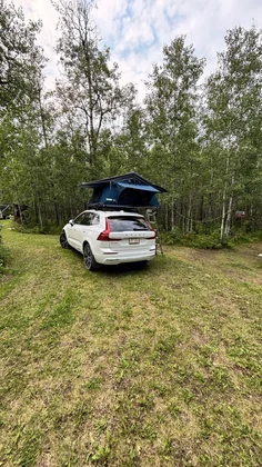Volvo XC60 with rooftop tent parked at a forest campsite